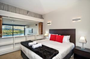 a bedroom with a large bed with red pillows and a window at Pure Retreat Lake View in Queenstown