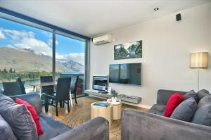 Sala de estar con sofás, TV y mesa en Pure Retreat Lake View en Queenstown