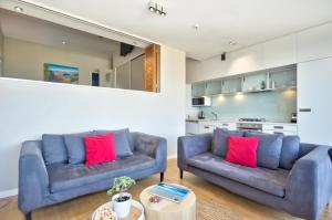 a living room with two blue couches and red pillows at Pure Retreat Lake View in Queenstown