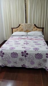 a bed with a purple and white comforter on it at Cantinho do SOSSEGO, a 2 km da praia de Itapuã, no centro da cidade, wifi, ideal para CASAL in Vila Velha