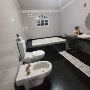 y baño con aseo blanco y bañera. en Cantinho do SOSSEGO, a 2 km da praia de Itapuã, no centro da cidade, wifi, ideal para CASAL en Vila Velha