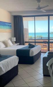 a hotel room with two beds and a view of the ocean at Ocean View 33A Studio Pool Ocean View WIFI in Airlie Beach