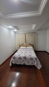 a bedroom with a bed with a floral bedspread at Cantinho do SOSSEGO, a 2 km da praia de Itapuã, no centro da cidade, wifi, ideal para CASAL in Vila Velha