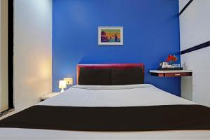 a blue bedroom with a large bed with a red headboard at OYO Hotel Blue Sea Near Chhatrapati Shivaji International Airport in Mumbai