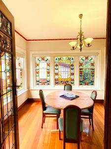 a dining room with a table and chairs and stained glass windows at Handcrafted stained-glass cottage, free parking in Hobart