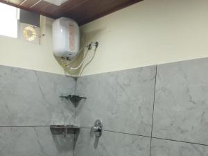 uma casa de banho com um chuveiro e um telefone na parede em High shine Homestay em Meppādi