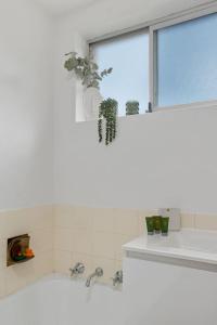 a bathroom with a tub and a window with a plant at Sea Vista Escape - A Charming Waterside Stay in Wollongong