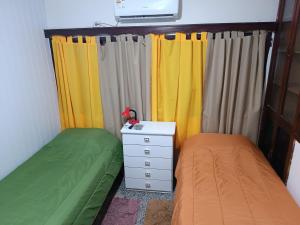 a bedroom with two beds and a dresser and curtains at Suculento Apart in Fray Bentos