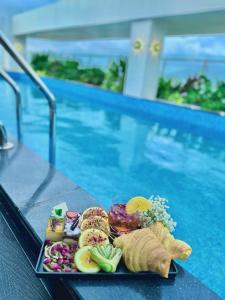 een dienblad met eten op een tafel naast een zwembad bij ViAn Hotel And Spa Danang in Da Nang