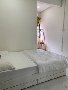 a bed in a room with a white wall at Juwita&Arjuna Homestay Teluk Senangin 