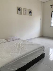 a bed in a white room with three pictures on the wall at Juwita&Arjuna Homestay Teluk Senangin 