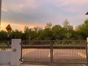 a fence with a gate with a yellow sign on it at Juwita&Arjuna Homestay Teluk Senangin in Kampong Batu Tiga