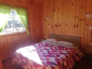 a bedroom with a bed in a wooden room at cabaña de 1 piso in Coñaripe