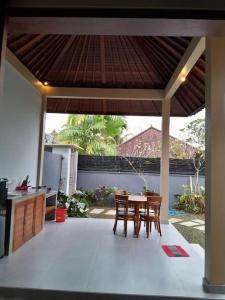 patio con tavolo e sedie sotto un tetto di Umah Landuh ad Ubud