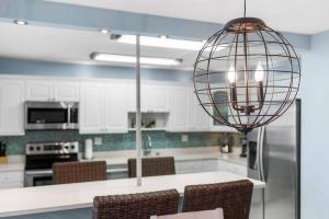 a kitchen with white cabinets and a pendant light at BEACHSIDE & Las Olas Getaway With Pool in Fort Lauderdale
