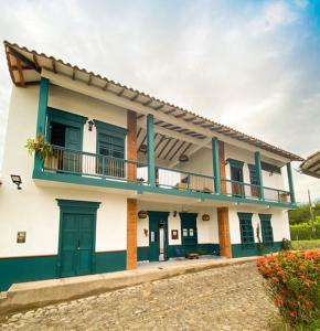 a white and green house with a balcony at Casa en Cauca Viejo con piscina, Jacuzzi y aire acondicionado in Jericó