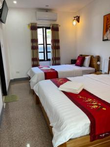 Habitación de hotel con 3 camas con sábanas rojas y blancas en Liberty Place en Luang Prabang