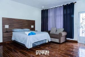 a bedroom with a bed and a chair in it at Marvelz Hotel 