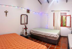 a bedroom with two beds and a cross on the wall at Casa Finca Genesis in Buga