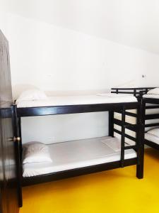 Amalaya Hostel في ريستريبو: سرير بطابقين أسود مع وسائد بيضاء