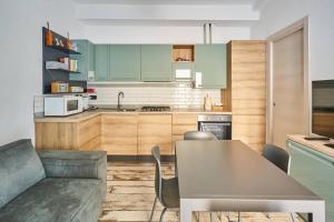 eine Küche mit grünen Schränken, einem Tisch und einer Couch in der Unterkunft appartamento a due passi dal mare in Bellaria-Igea Marina