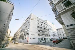 a white building on a street with parked cars at myNext - Campus Hostel in Vienna