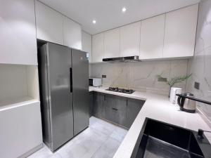 a kitchen with white cabinets and a stainless steel refrigerator at Shanghai World Expo Villa B&B - Near Lujiazui in Shanghai