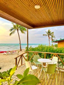 San Silvestre的住宿－Caribbean Escape Lodge，海滩上带桌椅的甲板