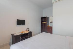 a bedroom with a bed and a desk and a tv at Sekar Bali Homestay in Gianyar