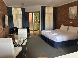 una camera d'albergo con letto e tavolo in vetro di Portarlington Beach Motel a Portarlington