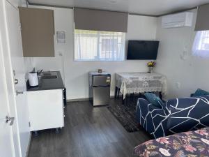 a room with a kitchen and a table and a couch at Self Contained En-Suite Private Bathroom, Private Entrance, Close to Shops & Hospital Homestay in Hamilton