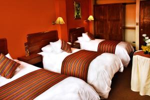 3 camas en una habitación de hotel con paredes de color naranja en IMPERIAL CUSCO HOTEL, en Cusco