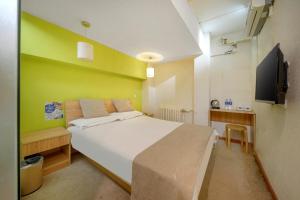 a bedroom with a white bed and a green wall at Harbin Hash International Youth Hostel Harbin West Station in Harbin