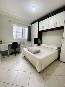 a bedroom with a bed and a desk and a chair at Apto à 100m da praia central in Balneário Camboriú
