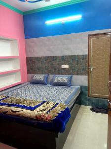 um quarto com uma cama com paredes azuis e cor-de-rosa em Garuda Guest House em Varanasi