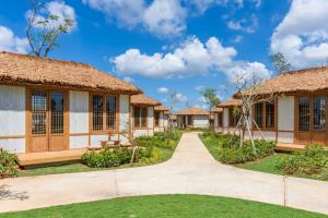 une rangée de cottages avec un chemin devant dans l'établissement K-Town Resort Phan Thiet, à Phan Thiết