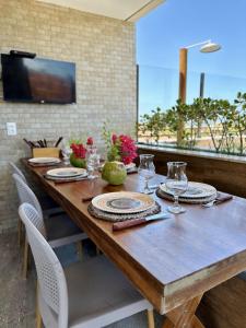 - une table en bois avec des assiettes et des verres à vin dans l'établissement Apê Jardins, à Flecheiras