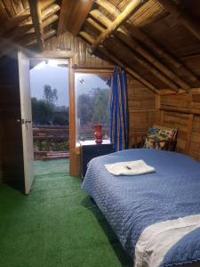 ein Schlafzimmer mit einem Bett und einem großen Fenster in der Unterkunft El Refugio del Oso de Anteojos in Fómeque