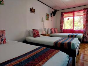 a room with three beds and a window at Chinitas Eco Lodge in Tortuguero