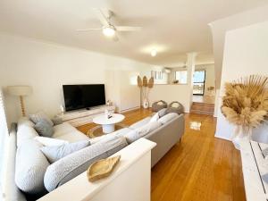 ein Wohnzimmer mit einem Sofa und einem TV in der Unterkunft The Scarborough Beach House - Walk to the beach! in Perth