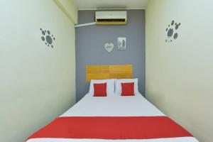 Schlafzimmer mit einem Bett mit roter und weißer Bettwäsche in der Unterkunft Dimensi Hotel in Kampong Alor Gajah