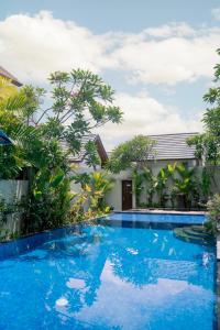 una piscina frente a una casa con árboles en The Calna Villa Bali, en Kuta