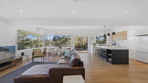 CopacabanaTreetops At Copacabana Accom Holidays的一间带棕色沙发的客厅和一间厨房