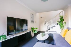 a living room with a large tv and a couch at Cozy 2 Bedroom Apartment Chippendale II in Sydney