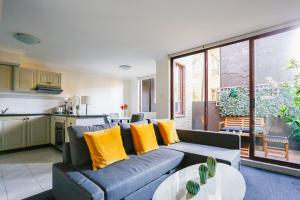 a living room with a blue couch and yellow pillows at Cozy 2 Bedroom Apartment Chippendale II in Sydney