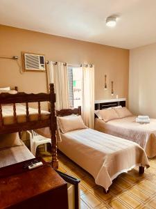 a bedroom with two beds and a window at Pousada Amanhecer do Itaguá in Ubatuba