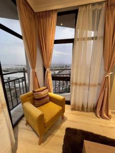 a living room with a yellow chair and a large window at Spacious 2 BR apartment near the airport in Addis Ababa