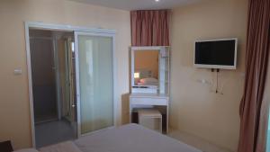 um quarto de hotel com uma cama e uma televisão em Palm Breeze 1-Bedroom Apartment em Praia de Rawai