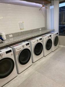 a row of washing machines in a laundry room at Loft Flow Parque Una com garagem! in Pelotas