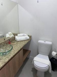a bathroom with a white toilet and a sink at Loft Flow Parque Una com garagem! in Pelotas